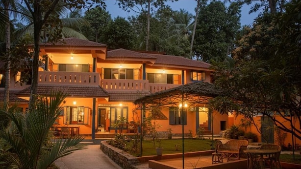 A two-story building with a balcony, a covered outdoor seating area, and a well-maintained garden. - Home City Homestay & Ayurvedic Clinic  (Kovalam)