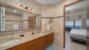 Un baño moderno con un espejo grande, lavamanos dobles y zona de ducha.