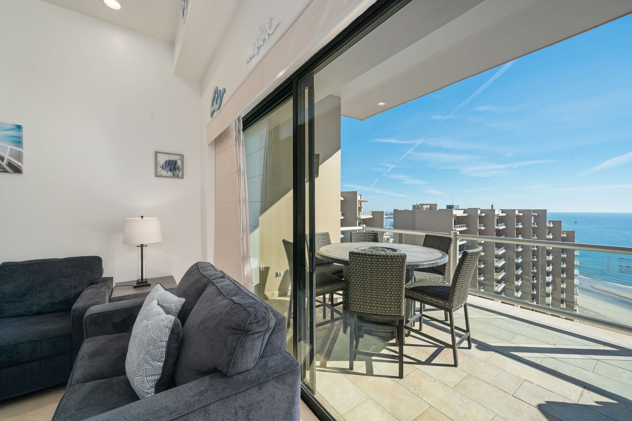 A balcony with a dining table and chairs, a sofa, and a lamp.