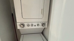 A compact, white laundry room with a washing machine and dryer stacked vertically. - Cozy Home in Lake Country (Kelowna)