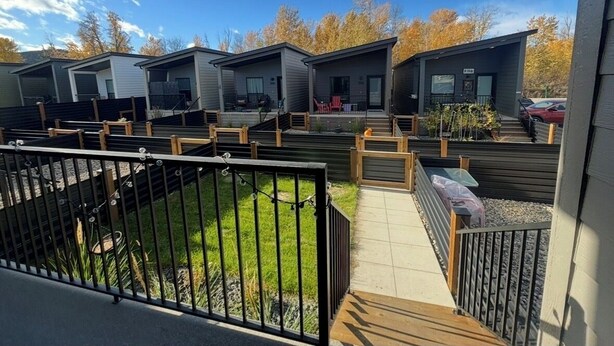 A row of modern, single-story cabins with individual balconies, arranged in a linear fashion along a paved pathway. - Cozy Home in Lake Country (Kelowna)