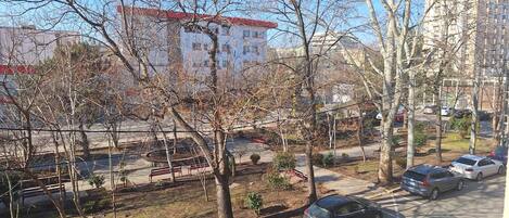 Un espace de stationnement avec plusieurs voitures, une aire de jeux avec un banc rouge et des arbres sans feuilles.