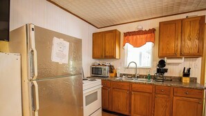 Eine Küche mit Holzschränken, einem Kühlschrank, einer Mikrowelle, einem Herd und einem Spülbecken.