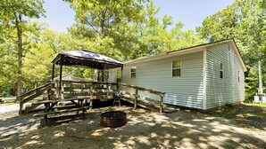 Eine Hütte mit überdachter Picknickgelegenheit, Grill und kleiner Sitzgruppe im Freien.