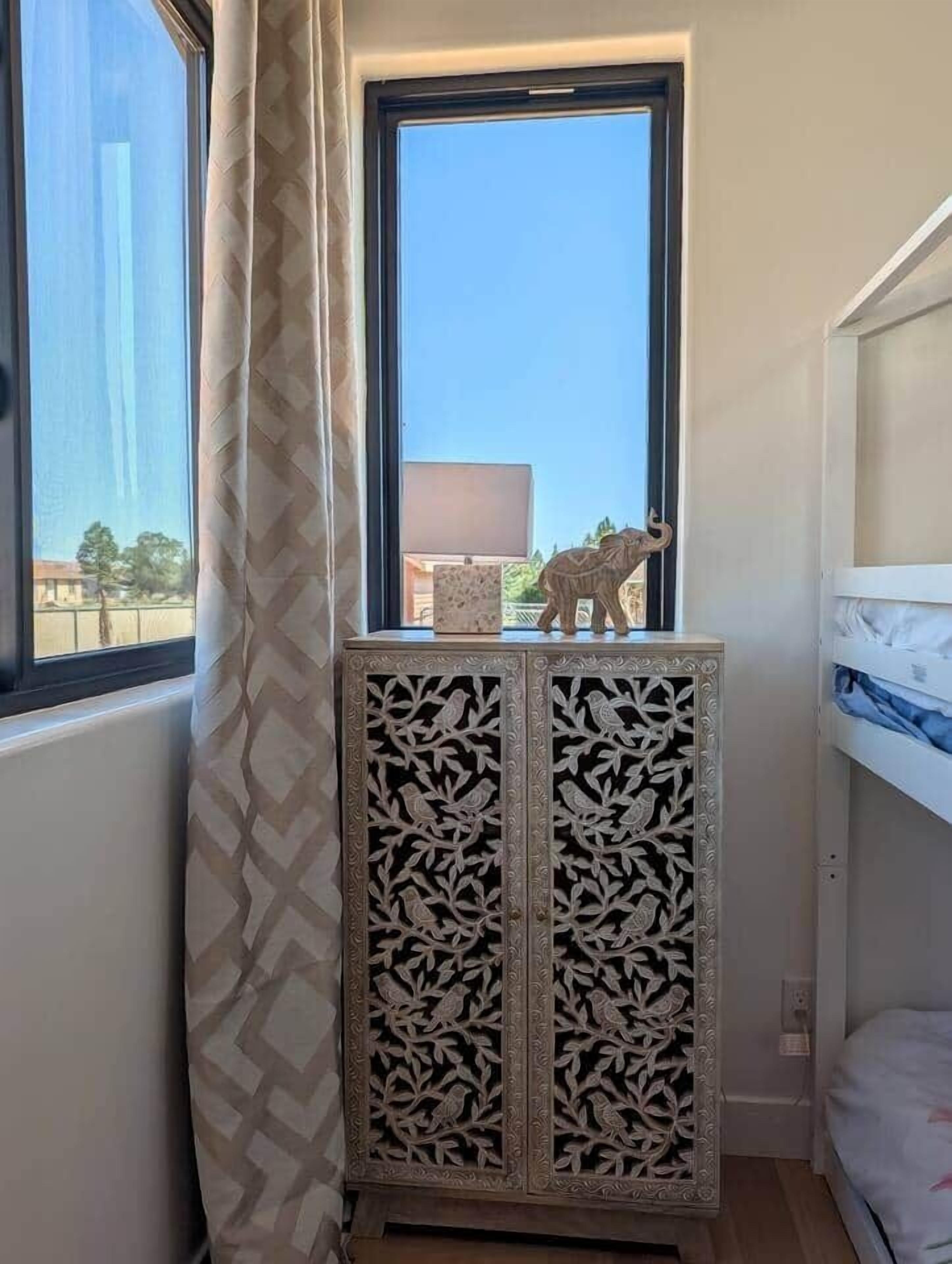 Quarto nos cantos com janela, um armário com detalhes entalhados e uma cama.