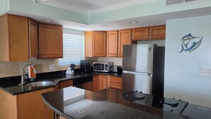 A kitchen with wooden cabinets, a stainless steel refrigerator, a microwave, a toaster, and a sink. -  Treasure Island condo with pool and jacuzzi (Treasure Island)