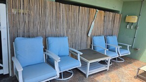 A seating area with four blue cushioned chairs and a small table, set against a bamboo wall. -  Treasure Island condo with pool and jacuzzi (Treasure Island)