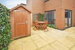 A wooden gate, a brick building, and a patio with a table and chairs. - 3BDR Kiln Side | Private Parking | Garden (Stoke-on-Trent)