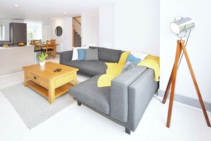 Ein modernes Wohnzimmer mit einem grauen Ecksofa, einem Holztisch und einer Stehlampe.