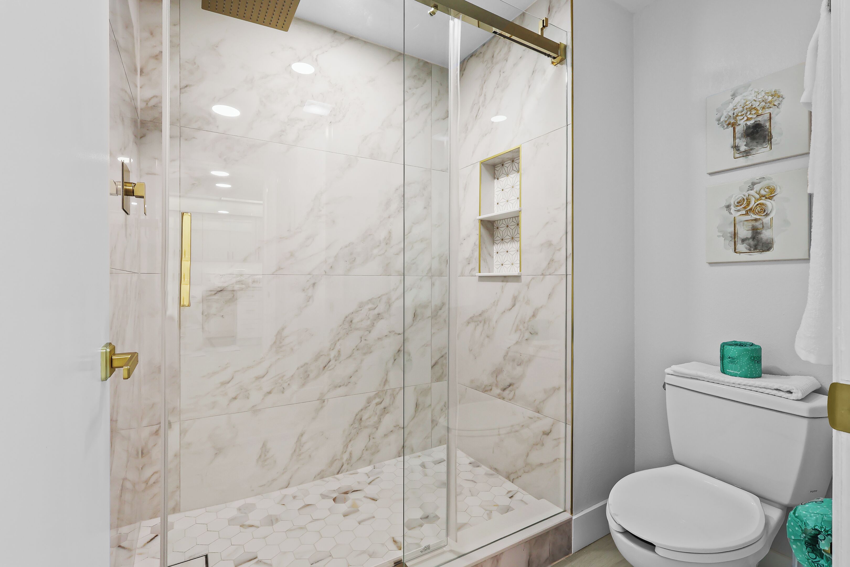 Een badkamer met een douchecabine, toilet en decoratieve wandkunst.