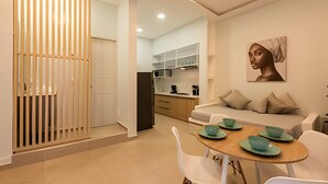 Een moderne woonkamer met een bank, een eettafel met groene borden en een keuken op de achtergrond.
