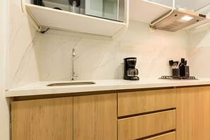 A modern kitchen with a white countertop, a stainless steel faucet, a coffee maker, and wooden cabinets. - Spectacular apt in the Historic Center - Zaher F (Cartagena)