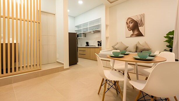 Een moderne eetruimte met een ronde tafel, witte stoelen en een keuken op de achtergrond.