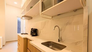 A modern kitchen with a marble backsplash, a stainless steel sink, and wooden cabinets. - Apt with balcony in the Historic Center - Zaher G (Cartagena)