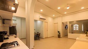 A modern hotel room with a kitchenette, a dining area, and a seating area with a view of the city. - Apt with balcony in the Historic Center - Zaher G (Cartagena)