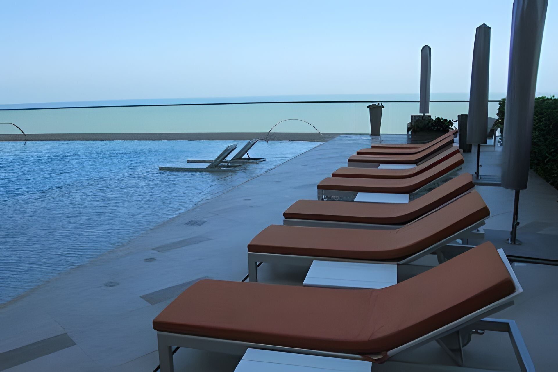 A poolside area with sun loungers and a view of the sea.