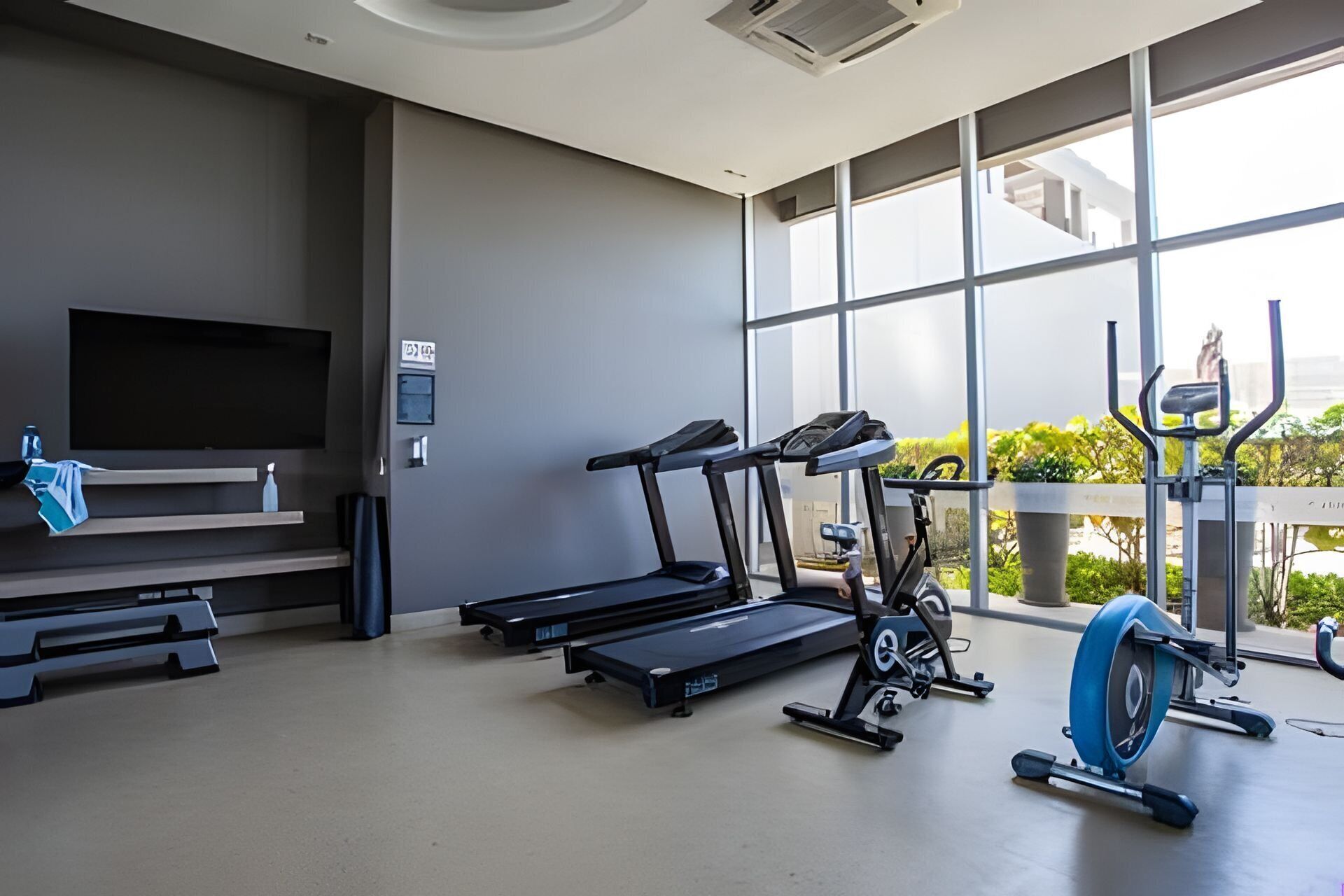 Ein modernes Fitnessstudio mit Trainingsgeräten, einer Bank und einem Fernseher.