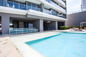 En modern byggnad med en swimmingpool, utomhusplats och en person nära ingången.