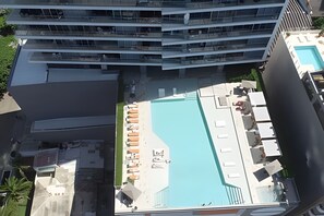 Ett högt hotell med en takterrass där det finns en pool, solstolar och en liten bar.
