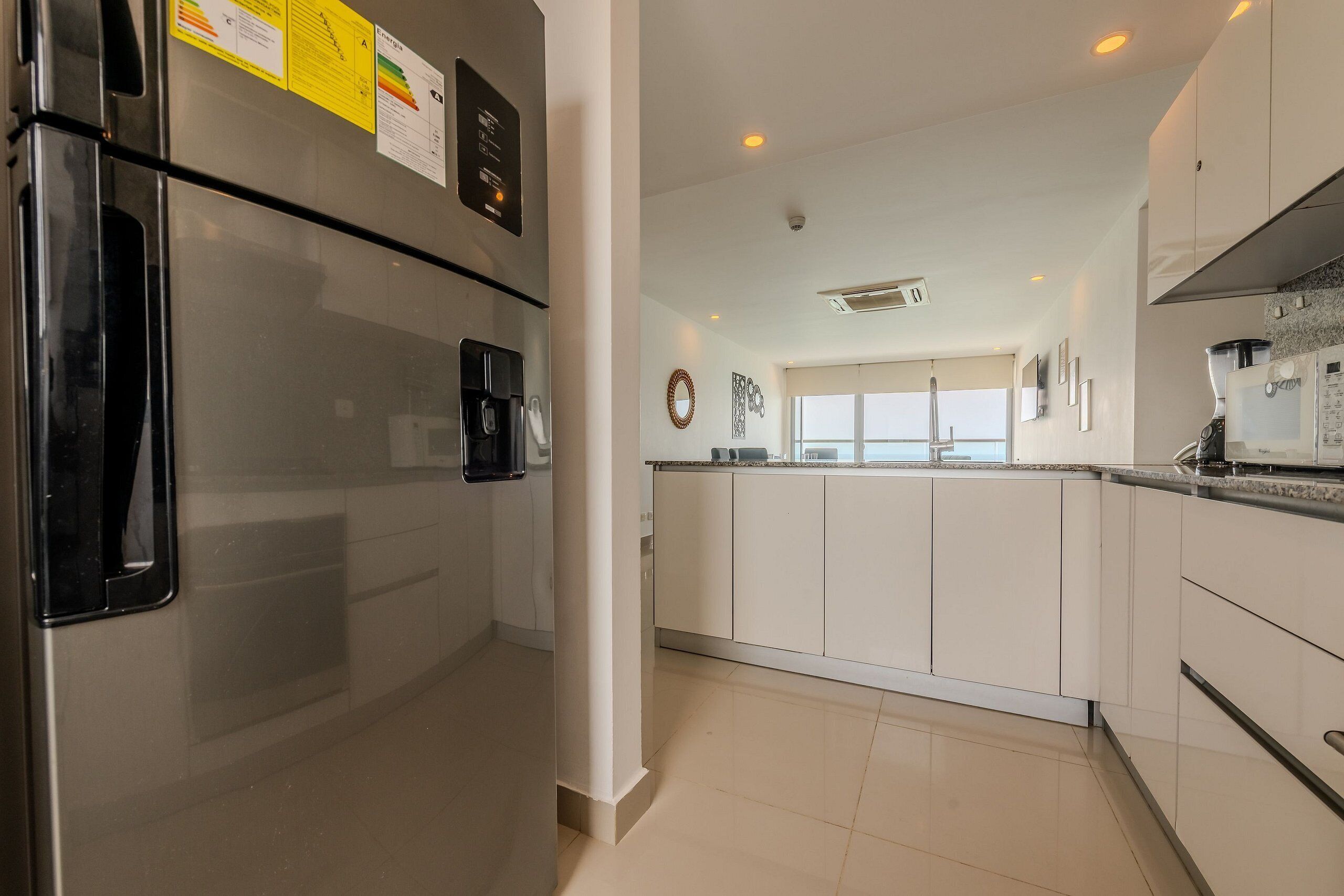 A modern kitchen with white cabinets, a stainless steel refrigerator, and a built-in oven.