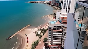 Eine Küstenstadt mit modernen Gebäuden, einem Strand und blauem Himmel.
