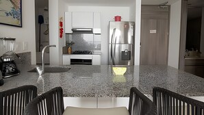 A modern kitchen with a stainless steel refrigerator, a gas stove, and white cabinets. - Spectacular 1 Bedroom Apt - 14th Floor Morros City (Cartagena)