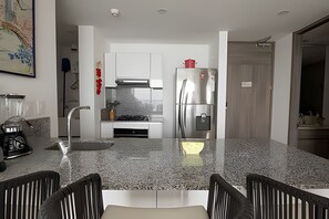 Eine moderne Küche mit einem Edelstahlkühlschrank, einem Gasherd und weißen Schränken.