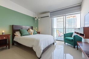 A modern hotel room with a large bed, green walls, a balcony with a view of buildings, and a small seating area. - Spectacular 2-bd apt on the 16th floor- Infinitum (Cartagena)