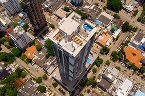An aerial view of a high-rise building with a rooftop pool, surrounded by other buildings and greenery. - Spectacular 2-bd apt on the 16th floor- Infinitum (Cartagena)
