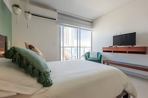 Ein modernes Hotelzimmer mit einem großen Bett, einem an der Wand befestigten Fernseher und einem Balkon mit Stadtblick.