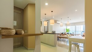 Une cuisine moderne dotée d’un îlot central, de luminaires suspendus et offrant une vue sur la ville grâce à de grandes fenêtres.