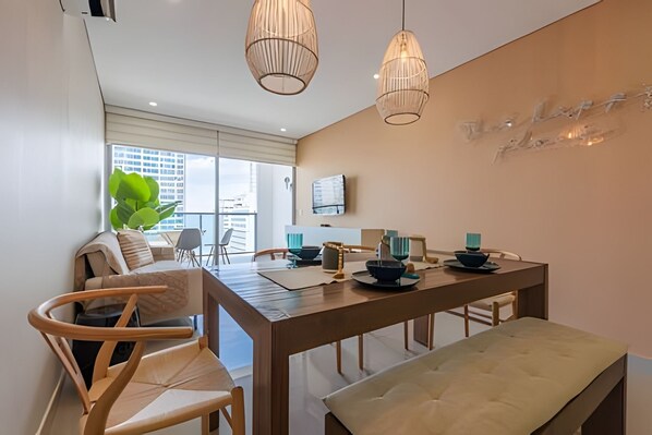 A modern dining area with a wooden table, chairs, and hanging pendant lights. - Spectacular 2-bd apt on the 16th floor- Infinitum (Cartagena)