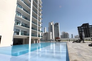 A modern building with a swimming pool, multiple balconies, and a clear view of surrounding high-rise buildings. - Spectacular 2-bd apt on the 16th floor- Infinitum (Cartagena)