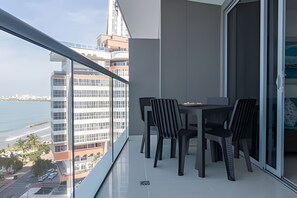 A balcony with a table and chairs, overlooking a cityscape and water. - Morros City - Spectacular Ocean View Apt, 8th Floor (Cartagena)
