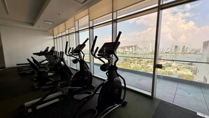 Uma academia com máquinas de cardio e vista da cidade através de grandes janelas.