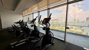 A gym with cardio machines and a city view through large windows. - H2 Luxury 1 Bd Apt, 23rd Floor W/House Help (Cartagena)