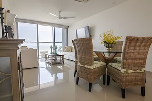 A modern living room with a glass table, wicker chairs, a TV, and a view through large windows. - Luxurious 2-bd apt on the 26th Floor - Morros City (Cartagena)
