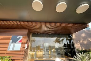 A modern building entrance with a wooden slatted roof, glass doors, and three ceiling lights. - Luxurious 1 Bd Apt on the 17th Floor - H2 Hyatt (Cartagena)