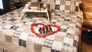 A bed with a quilt, a tray with drinks, and a heart-shaped arrangement of chocolates. - Green Briar Cabin a beautiful private log cabin (Marietta)