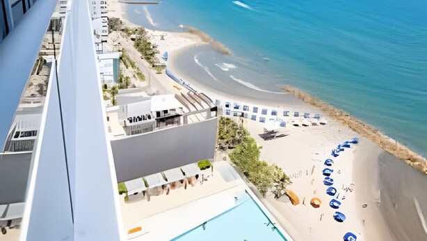 Ein Hochhaus-Hotel mit Pool und Blick auf den Strand.
