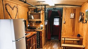 Cocina compacta con armarios de madera, un refrigerador y una zona de comedor con un banco.