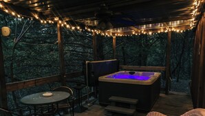 Une terrasse en bois avec un jacuzzi, une table et des chaises.