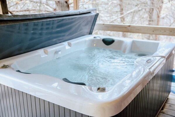 A hot tub with a wooden deck and a metal railing.