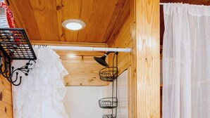 Un intérieur en bois agrémenté d’un rideau blanc à volants, d’une poignée de porte noire et d’un luminaire au plafond.