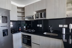 Eine moderne Küche mit Edelstahlgeräten, einer schwarzen Arbeitsplatte und hellen Holzschränken.
