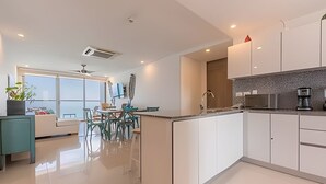 Une cuisine moderne avec des meubles blancs, un îlot central et un coin repas comprenant une table et des chaises.