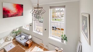 A modern living room with a grey sofa, a wooden coffee table, and a hanging light fixture. - Stylish Stay w/ All you Need- The Old Grammar School (Kibworth)