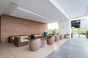 A modern reception area with a wooden wall, seating, and a glass door leading outside. - Spectacular Bay View! 26th Floor H2 Hyatt (Cartagena)