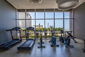 A gym with various exercise equipment and large windows offering a view of the outdoors. - Beautiful 2 Bedroom Apt on the 11th Floor-Morros City (Cartagena)