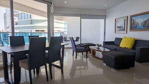 A modern living room with a dining area, a sofa with a yellow pillow, and a coffee table. - Spectacular Ocean View - Infinito Building 1802 (Cartagena)
